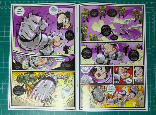 An open printed comic book or manga page laid flat on a green cutting mat. The page contains multiple illustrated panels with a purple, yellow, gray, and black action scene, speech bubbles, and character faces.